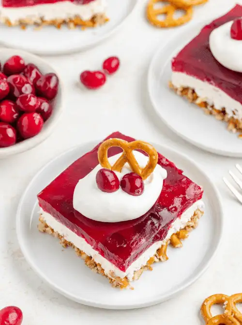 A slice of cranberry pretzel salad topped with whipped cream, cranberries, and a pretzel twist—an easy, festive option for Budget-Friendly Thanksgiving Vegetable Sides.
