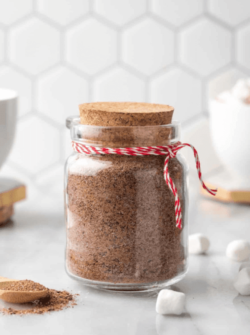 Homemade hot cocoa mix in a glass mason jar tied with red twine, a festive idea for DIY Christmas gifts and mason jar recipes.S