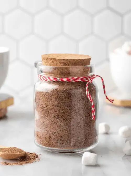Homemade hot cocoa mix in a glass mason jar tied with red twine, a festive idea for DIY Christmas gifts and mason jar recipes.S