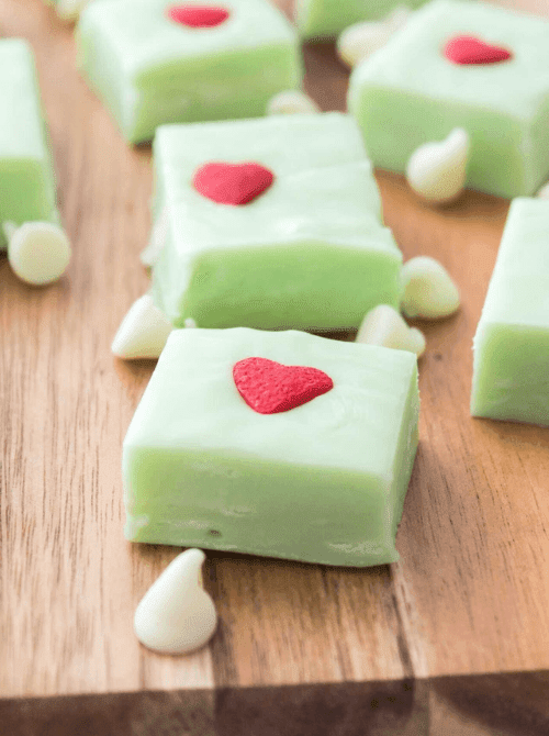 Green Grinch fudge squares topped with red candy hearts, a whimsical DIY Christmas gift and easy edible gift idea for the holiday season.