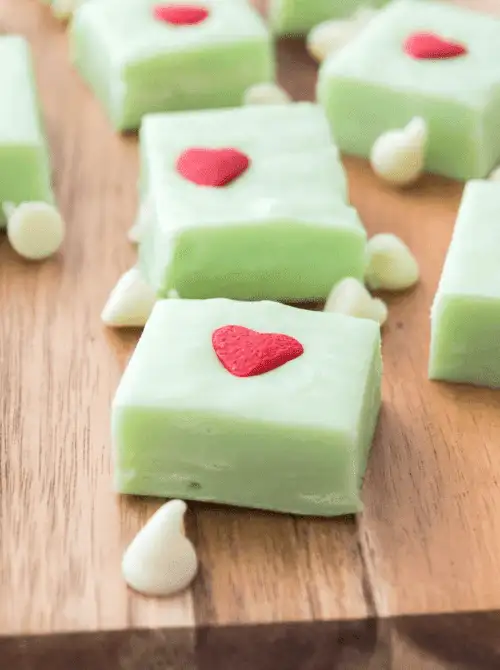 Green Grinch fudge squares topped with red candy hearts, a whimsical DIY Christmas gift and easy edible gift idea for the holiday season.