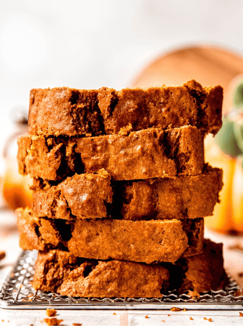 Stack of thick, golden-brown slices of pumpkin bread on a cooling rack — a delicious idea for what to do with leftover pumpkin puree and a tempting choice for easy pumpkin bread recipes.
