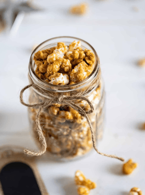Homemade caramel popcorn packed in a mason jar and tied with rustic twine, a sweet and crunchy DIY Christmas gift idea from mason jar recipes.