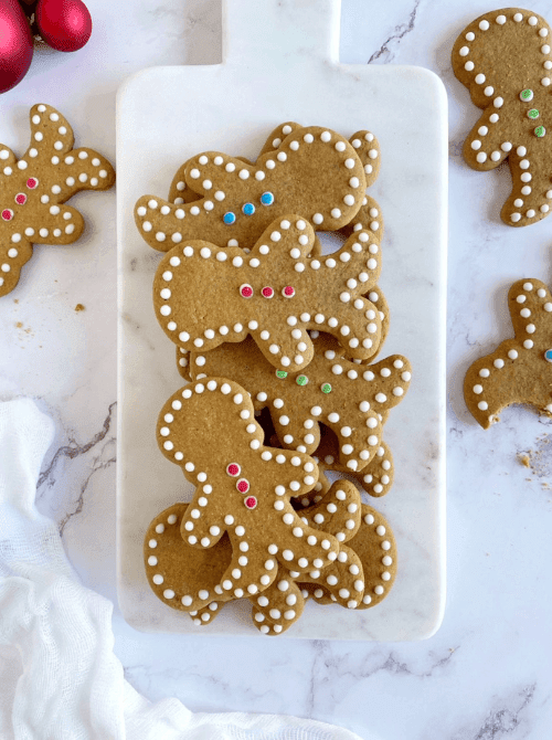 Decorated gingerbread men cookies on a marble board, a festive DIY Christmas gift idea featuring cookies and bars.