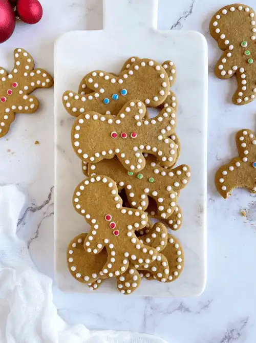 Decorated gingerbread men cookies on a marble board, a festive DIY Christmas gift idea featuring cookies and bars.