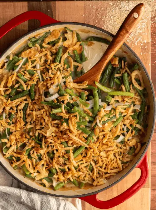 Green bean casserole topped with crispy fried onions in a red skillet—an easy, comforting classic for Budget-Friendly Thanksgiving Vegetable Sides.
