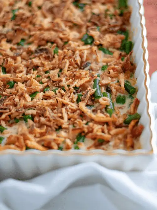 Green bean casserole topped with crispy fried onions and baked in a white scalloped dish—an easy crowd favorite for Budget-Friendly Thanksgiving Vegetable Sides.