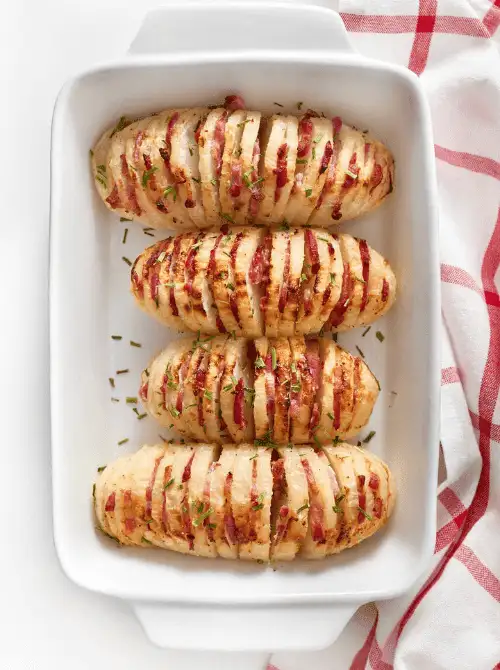Hasselback turnips layered with bacon and herbs in a white baking dish—an eye-catching, low-cost twist for Budget-Friendly Thanksgiving Vegetable Sides.S