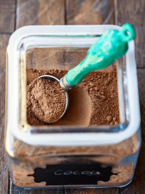 Hot chocolate in a glass jar with a scoop, perfect for mason jar recipes and DIY Christmas gifts.