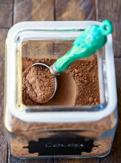 Hot chocolate in a glass jar with a scoop, perfect for mason jar recipes and DIY Christmas gifts.