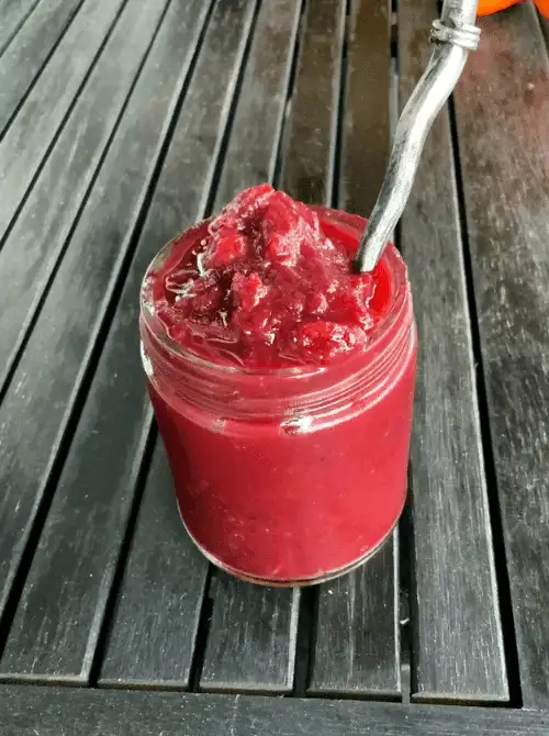 Jar of homemade cranberry sauce served with a spoon, a colorful and budget-friendly Thanksgiving side dish perfect for holiday gatherings.