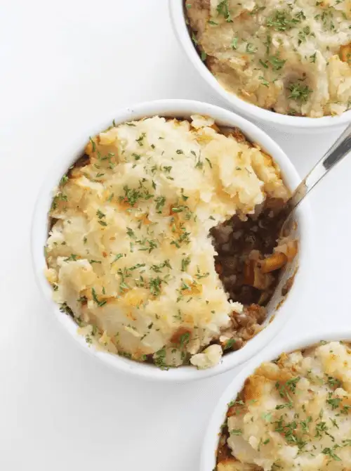 Individual ramekins of lentil Shepherd’s Pie topped with golden mashed potatoes – a hearty plant-based option for what to make with Thanksgiving leftovers and recipes that stretch your budget.