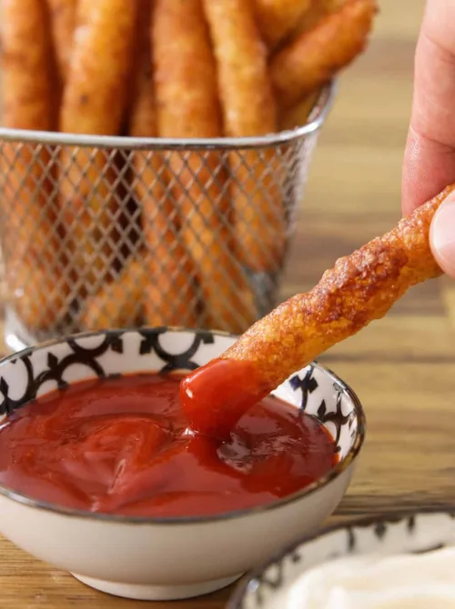Crispy mashed potato fries dipped in ketchup – a fun and budget-friendly idea for what to make with Thanksgiving leftovers and recipes that stretch your budget.