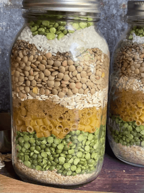 Layered soup mix with lentils, split peas, pasta, and spices in a mason jar, a hearty mason jar recipe and budget-friendly DIY Christmas gift.