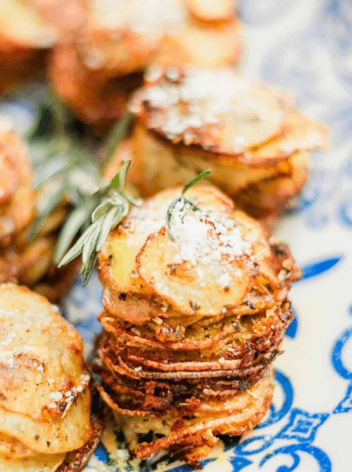 Stacked muffin tin potatoes garnished with rosemary and parmesan, featured in Budget-Friendly Thanksgiving Sides and Easy Potato Recipes for a crispy holiday dish.