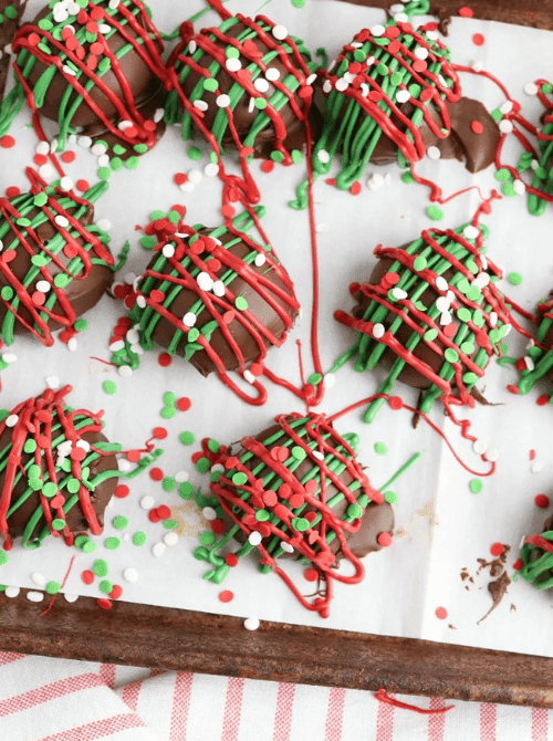 Chocolate covered Oreos drizzled with red and green icing and sprinkles, a festive DIY Christmas gift idea featuring cookies and bars.