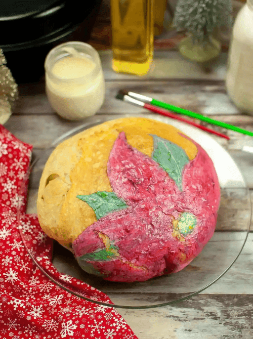 Homemade sourdough loaf decorated with a painted poinsettia design, a creative DIY Christmas gift and easy edible gift idea for the holidays.