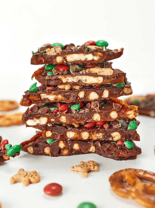 Stack of pretzel Christmas crack bark with chocolate, caramel, and red and green candies, a salty-sweet DIY Christmas gift and easy edible gift idea for the holidays.