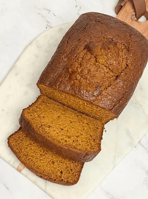 Golden brown pumpkin bread loaf with slices on a marble cutting board — a perfect example of what to do with leftover pumpkin puree and a go-to option for easy pumpkin bread recipes.