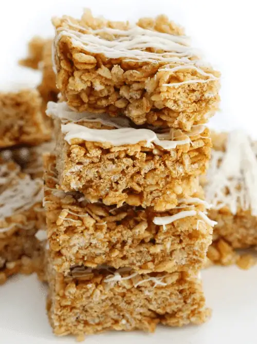 Stack of pumpkin spice Rice Krispie treats drizzled with white chocolate—easy, festive, and budget-friendly make-ahead Halloween party food for dessert tables or snack bars.