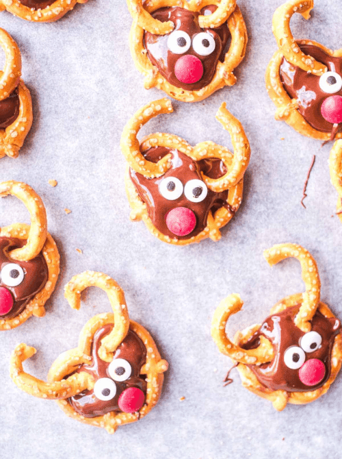 Holiday pretzel reindeers topped with chocolate, candy eyes, and red noses, a whimsical DIY Christmas gift and easy edible gift idea for festive celebrations.