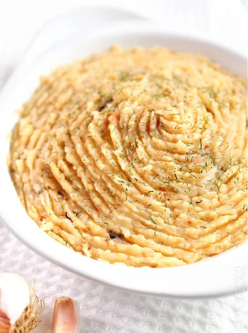 Mashed roasted turnips with garlic in a white dish, topped with herbs—an easy, low-carb alternative for Budget-Friendly Thanksgiving Vegetable Sides.