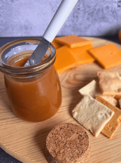 Homemade apple butter in a small mason jar served with cheese and crackers, a cozy fall-inspired mason jar recipe and DIY Christmas gift idea.S