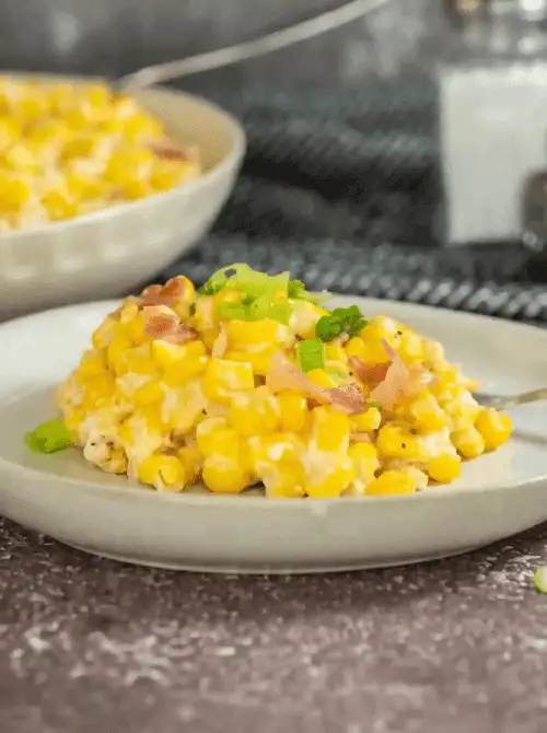 Creamy corn casserole topped with green onions and bacon bits, served on a neutral plate—an indulgent and Budget-Friendly Thanksgiving Vegetable Side everyone will love.