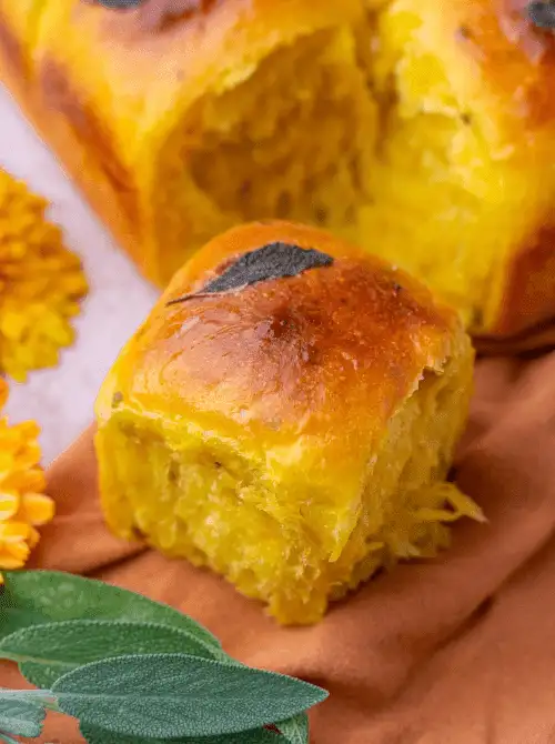 Golden sourdough sweet potato dinner roll topped with sage – a soft and flavorful idea for what to make with Thanksgiving leftovers and recipes that stretch your budget.