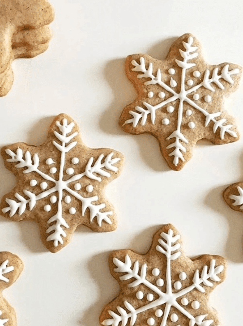 Snowflake sugar cookies decorated with white icing, a festive DIY Christmas gift idea featuring cookies and bars.