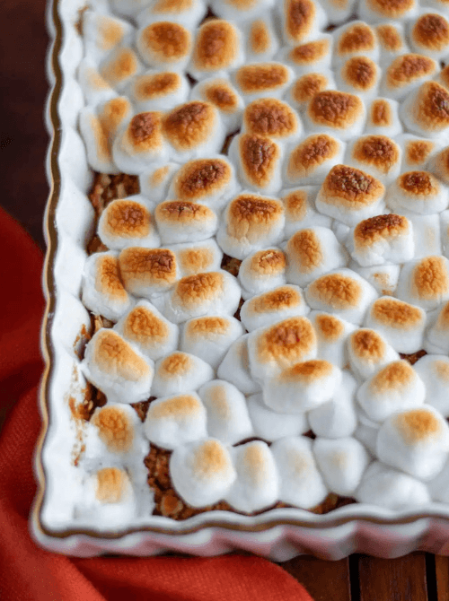 Sweet potato casserole topped with golden-brown toasted marshmallows in a white baking dish, featured in Budget-Friendly Thanksgiving Sides and Easy Potato Recipes for a nostalgic holiday favorite.S