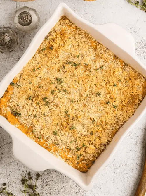 Sweet potato casserole with golden breadcrumb topping and fresh herbs in a square baking dish, part of Budget-Friendly Thanksgiving Sides and Easy Potato Recipes for a savory holiday option.