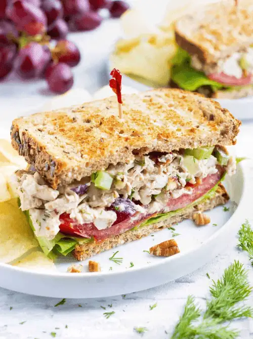 A fresh turkey salad sandwich with grapes, celery, and lettuce on whole grain bread, served with chips and pecans — a delicious idea for what to make with Thanksgiving leftovers and one of the best easy turkey recipes for lunch.