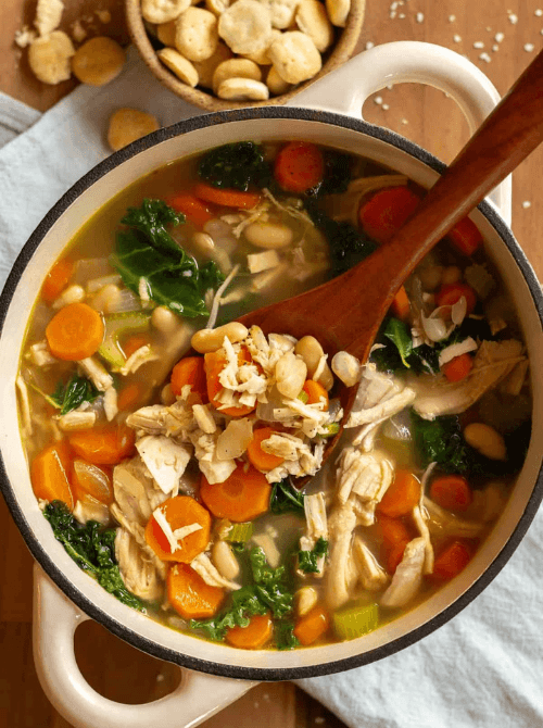 Hearty turkey and white bean soup with carrots, kale, and celery simmering in a pot — a cozy idea for what to make with Thanksgiving leftovers and one of the easiest turkey recipes for winter meals.