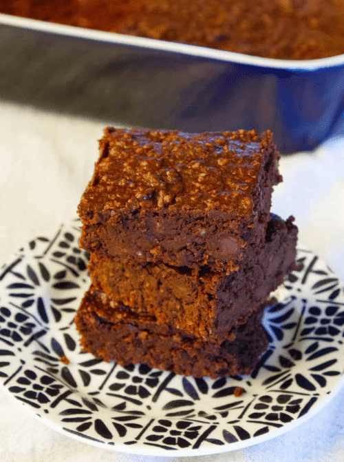 Stack of rich vegan chocolate fudge brownies on a patterned plate, a delicious DIY Christmas gift and easy edible gift idea for the holidays.