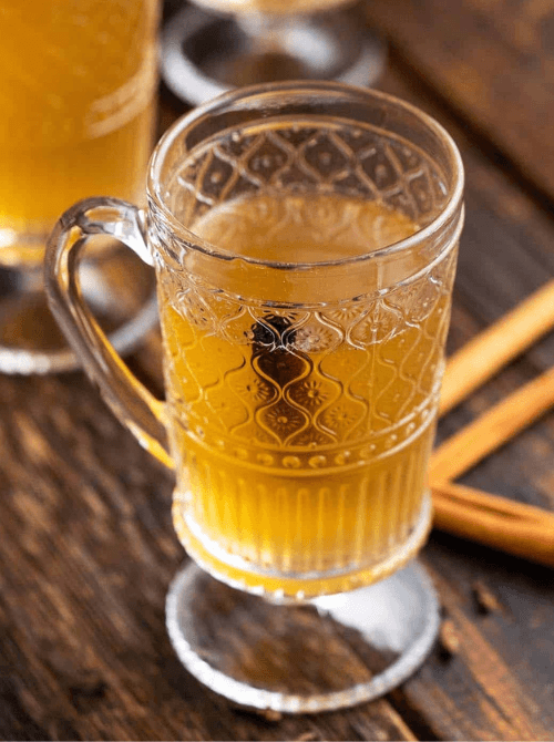 Homemade spiced honey liqueur served in a glass mug with cinnamon sticks, a unique mason jar recipe and DIY Christmas gift idea.