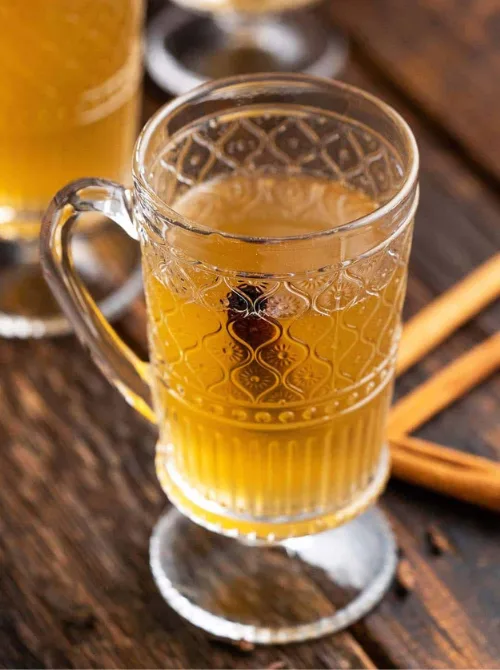 Homemade spiced honey liqueur served in a glass mug with cinnamon sticks, a unique mason jar recipe and DIY Christmas gift idea.