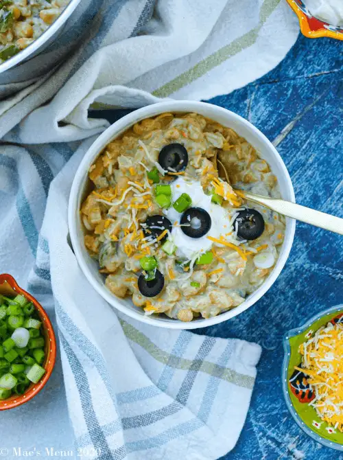 Bowl of creamy white bean and turkey chili topped with sour cream, shredded cheese, black olives, and green onions — a hearty idea for what to make with Thanksgiving leftovers and one of the easiest turkey recipes for cold nights.