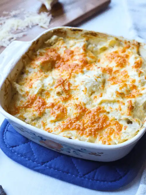 Baked artichoke dip topped with golden melted cheese in a casserole dish, a warm and comforting choice for Party Dips for the Holidays and Cheesy Dips.