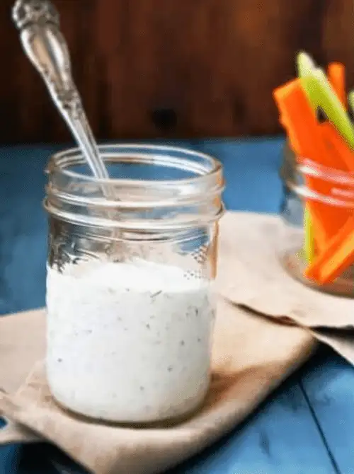Creamy homemade ranch dressing in a mason jar with a spoon, served with carrot and celery sticks—an easy favorite for Party Dips for the Holidays and Cheesy Dips.