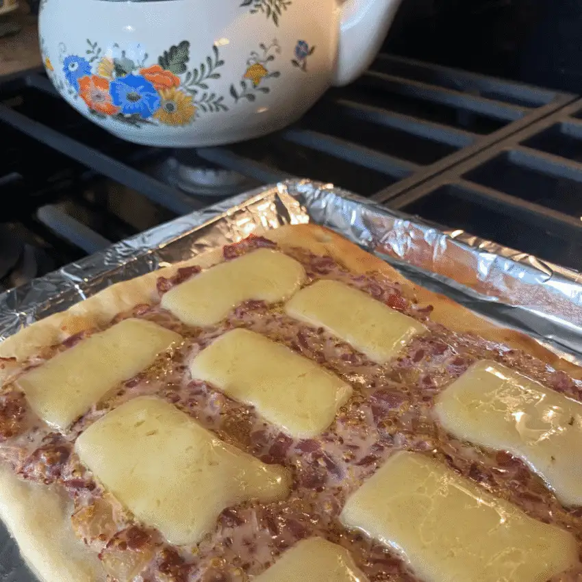 Homemade Oktoberfest sauerkraut pizza on a baking sheet, topped with caramelized onions, apples, and melted cheese fresh from the oven.