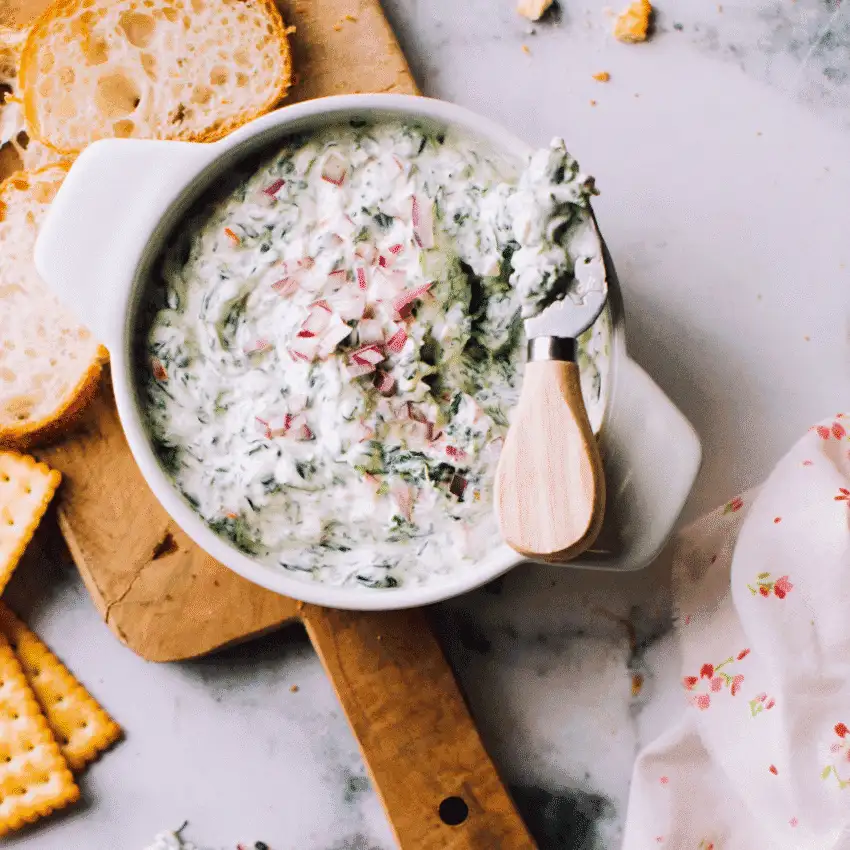Homemade sour cream spinach dip with fresh herbs, served with bread and crackers—a classic choice for Party Dips for the Holidays and Cheesy Dips.