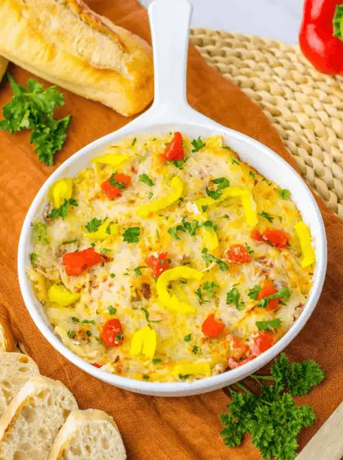 Warm cheesy dip baked in a white skillet with peppers and herbs, served with bread slices—a colorful option for Party Dips for the Holidays and Cheesy Dips.