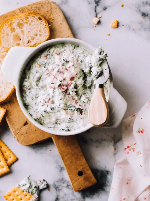 Homemade sour cream spinach dip with fresh herbs, served with bread and crackers—a classic choice for Party Dips for the Holidays and Cheesy Dips.