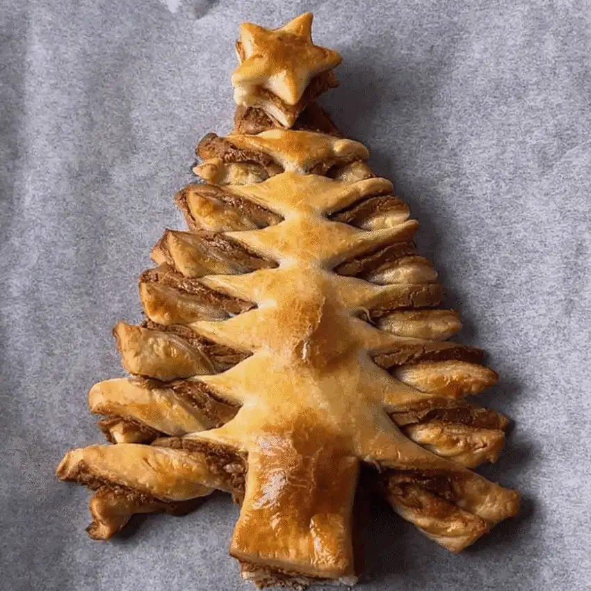 Biscoff Puff Pastry Christmas Tree with a golden star topper — a festive and easy finger food appetizer for Christmas party food ideas, featuring flaky layers of puff pastry and cookie butter spread for a budget-friendly holiday dessert or appetizer that looks impressive but costs less to make.