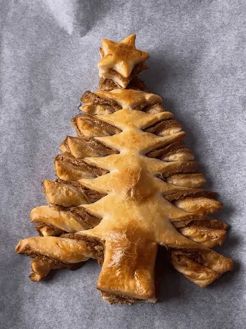 Biscoff Puff Pastry Christmas Tree with a golden star topper — a festive and easy finger food appetizer for Christmas party food ideas, featuring flaky layers of puff pastry and cookie butter spread for a budget-friendly holiday dessert or appetizer that looks impressive but costs less to make.