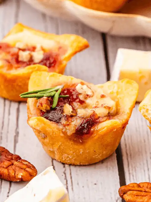 Cranberry Brie Bites topped with chopped pecans and fresh rosemary — an easy make-ahead Christmas appetizer that’s perfect for holiday entertaining, budget-friendly Christmas party food ideas, and festive finger food appetizers for a crowd.
