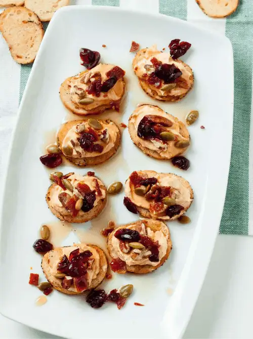 Brie and Fig Crostini topped with cranberries, pumpkin seeds, and honey drizzle — an elegant yet easy finger food appetizer for Christmas party food ideas that blends sweet and savory flavors, ideal for budget-friendly holiday entertaining and festive gatherings.