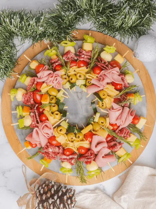 Charcuterie Wreath made with skewers of cheese, salami, ham, olives, and tomatoes — a festive and budget-friendly holiday appetizer perfect for Christmas party food ideas, easy finger food appetizers, and make-ahead Christmas entertaining for a crowd.