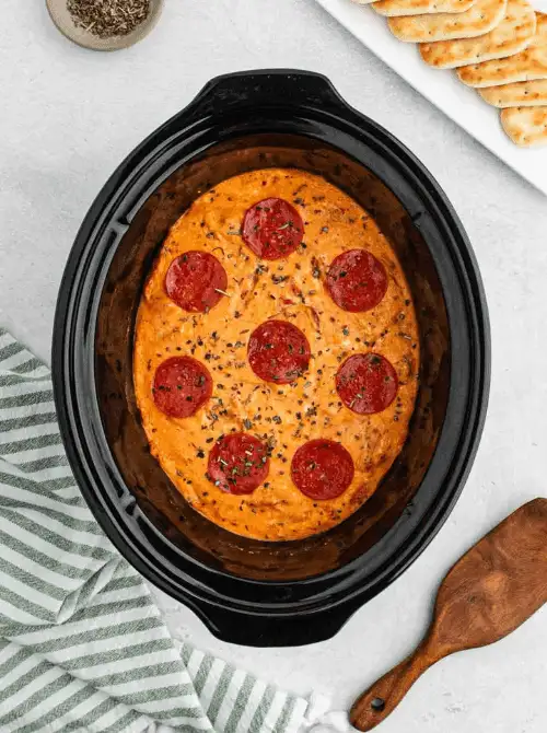 Slow cooker pepperoni pizza dip topped with herbs, a fun and hearty choice for Party Dips for the Holidays with Unique Twists.